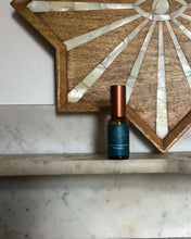 Small bottle with a copper cap on a marble surface with a decorative wooden frame in the background