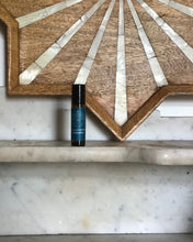 Small bottle on a marble surface with a decorative wooden wall panel in the background