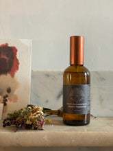 Bottle of chakra balancing with a grey label on a marble surface with flowers and a painting