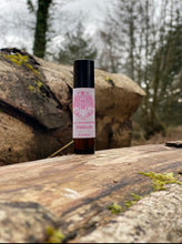 Roll-on bottle with pink label on a wooden surface outdoors