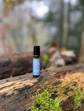 Small peace out roller of essential oil on a wooden log with a forest background