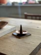 Incense cone on copper stand on a wooden board
