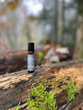 amber bottle with grey blue label let me breathe on a log in a woodland