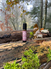 amber bottle with purple mindfulness label on a log in a woodland