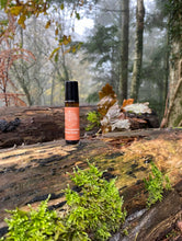 amber roller bottle 10ml roller on a log in a woodland