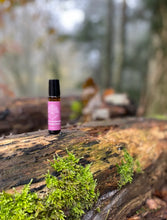 amber bottle with a pink label on a log in a woodland